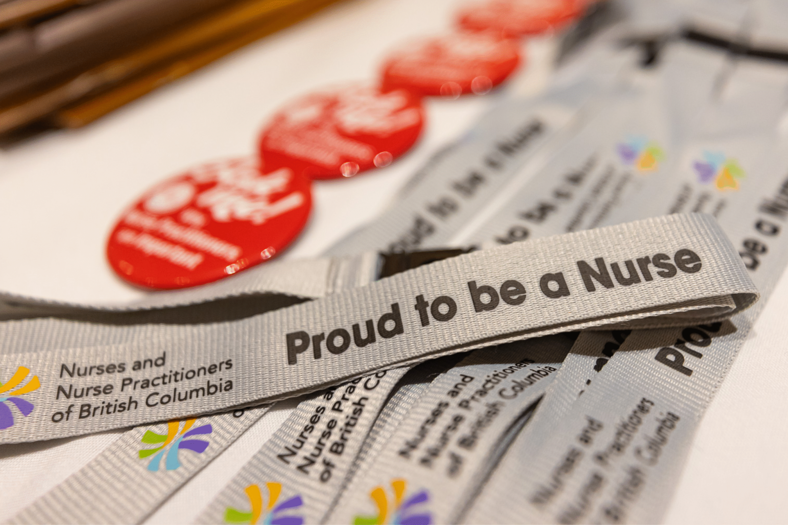 Close-up of an NNPBC lanyard on a table. The lanyard reads "Proud to be a Nurse"